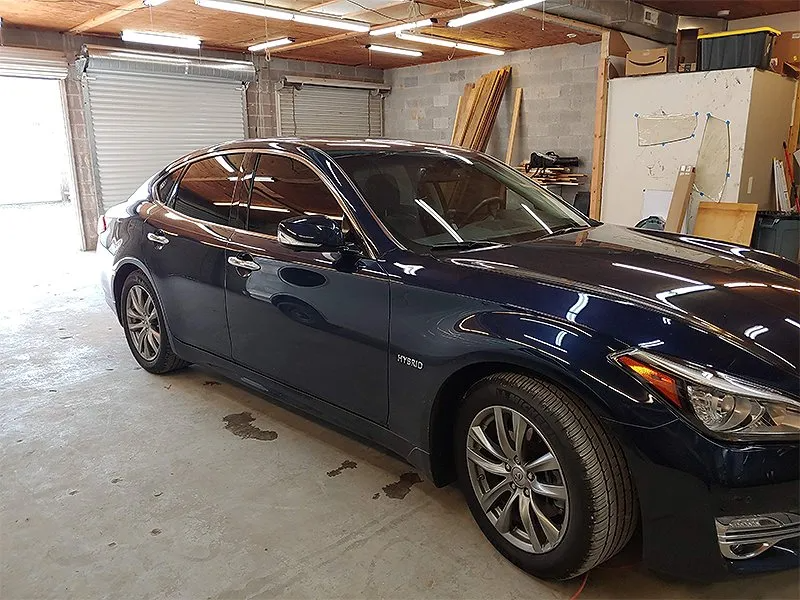 Dark blue sedan parked inside a garage, with tinted windows and a closed garage door.