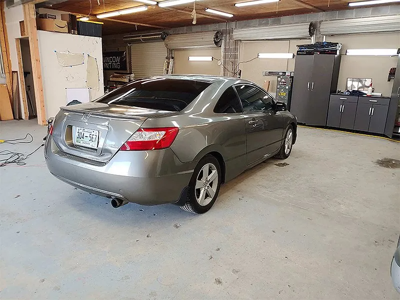 Gray Honda Civic coupe parked inside a garage, rear view.