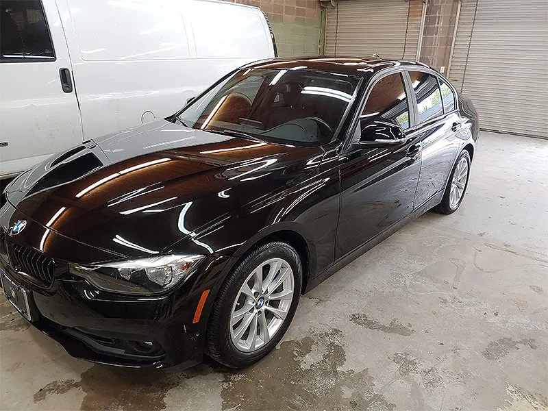 Black BMW sedan parked in a garage; white van in the background.