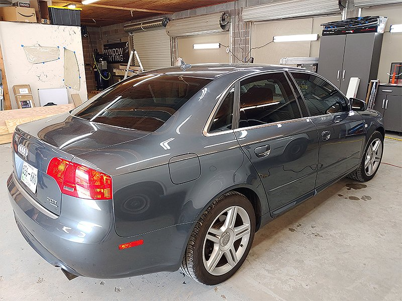 Gray Audi sedan parked in a garage, tinted windows, silver wheels.