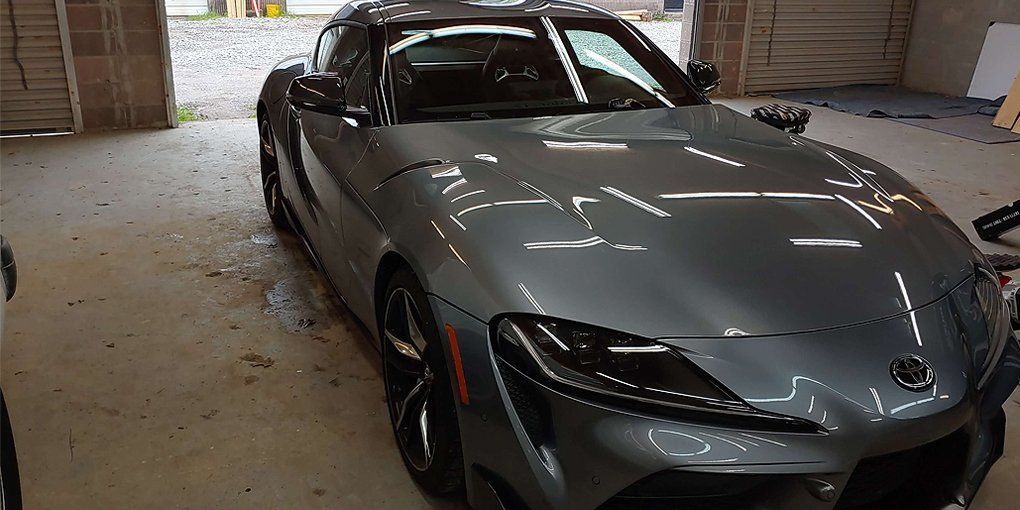 A gray Toyota Supra sports car parked in a garage.