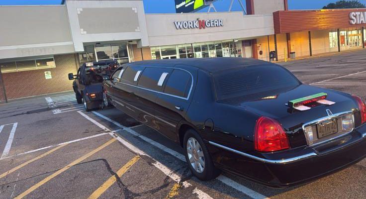Black limousine parked outside a Work World store.