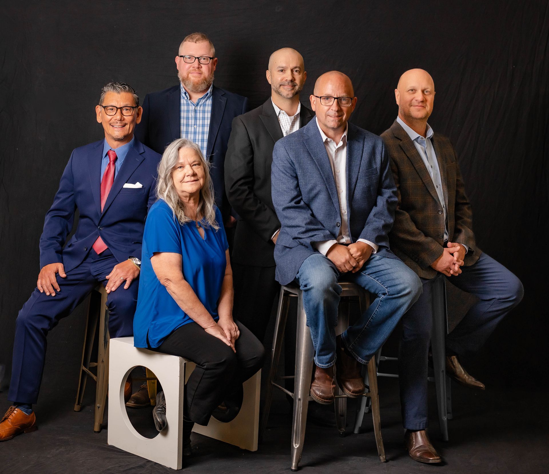 Group of people posing outdoors in front of a brick building with white columns.