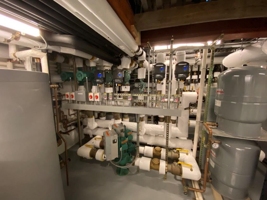 Mechanical room with pipes, tanks, and control panels. Gray and white colors dominate the scene.