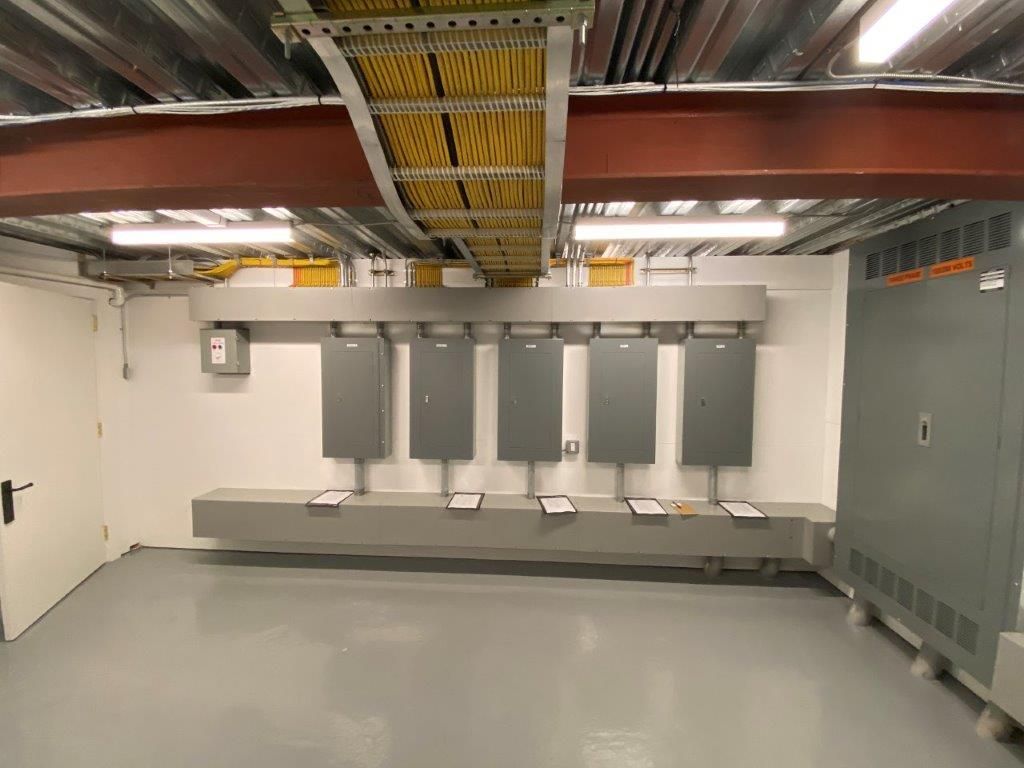 Electrical room with gray electrical panels and yellow wiring.