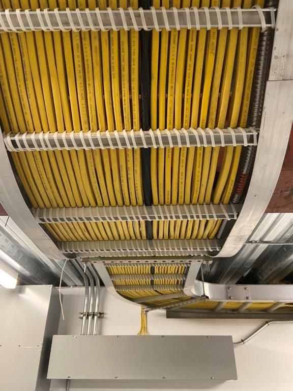 Yellow cables neatly arranged in a cable tray along the ceiling. White supports and metal structure.