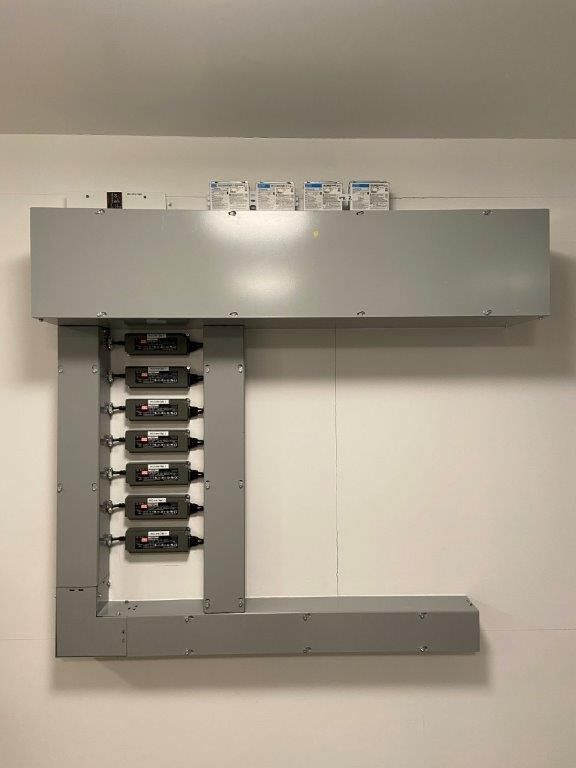 Gray electrical panel mounted on a white wall.