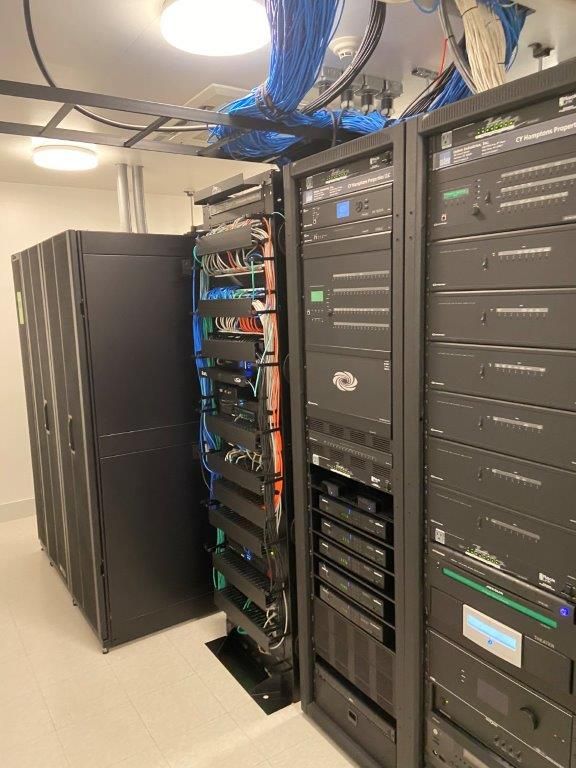 Server racks in a network room with blue and orange cables.