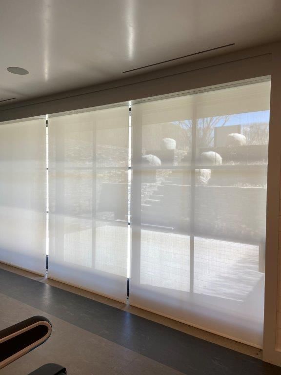 Large windows with light filtering blinds. Sunlight streams through, reflecting on the floor.