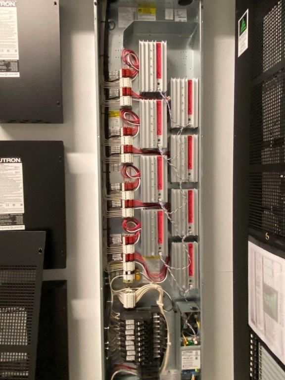 Open electrical panel with red and white wiring and several rectangular modules.