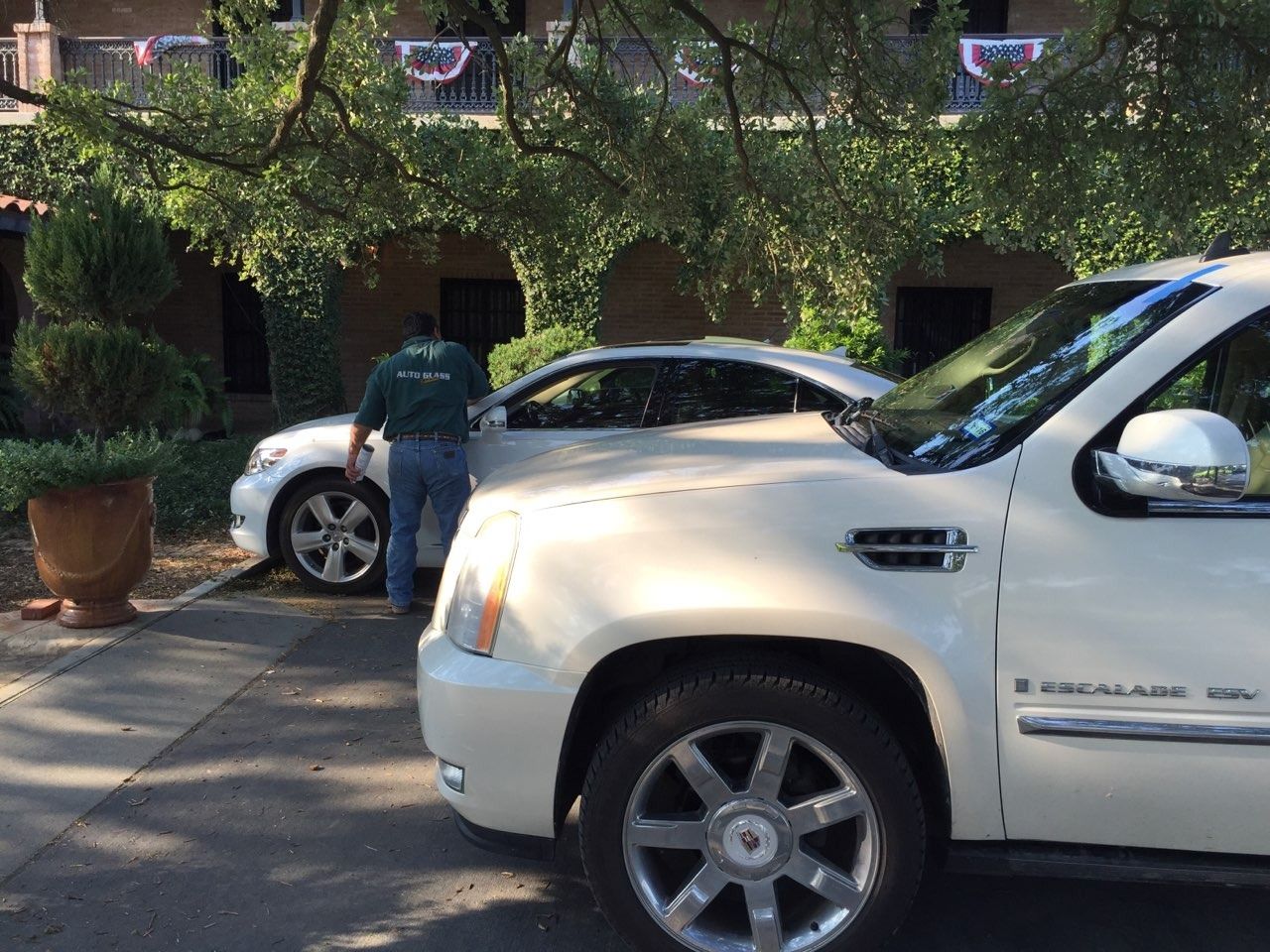 White SUV and car parked near a building; a person is standing by the car.