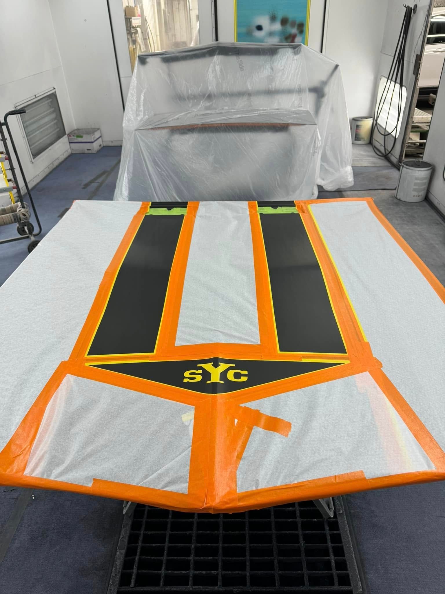 A large black and orange SIG graphic taped to the floor of a workshop.