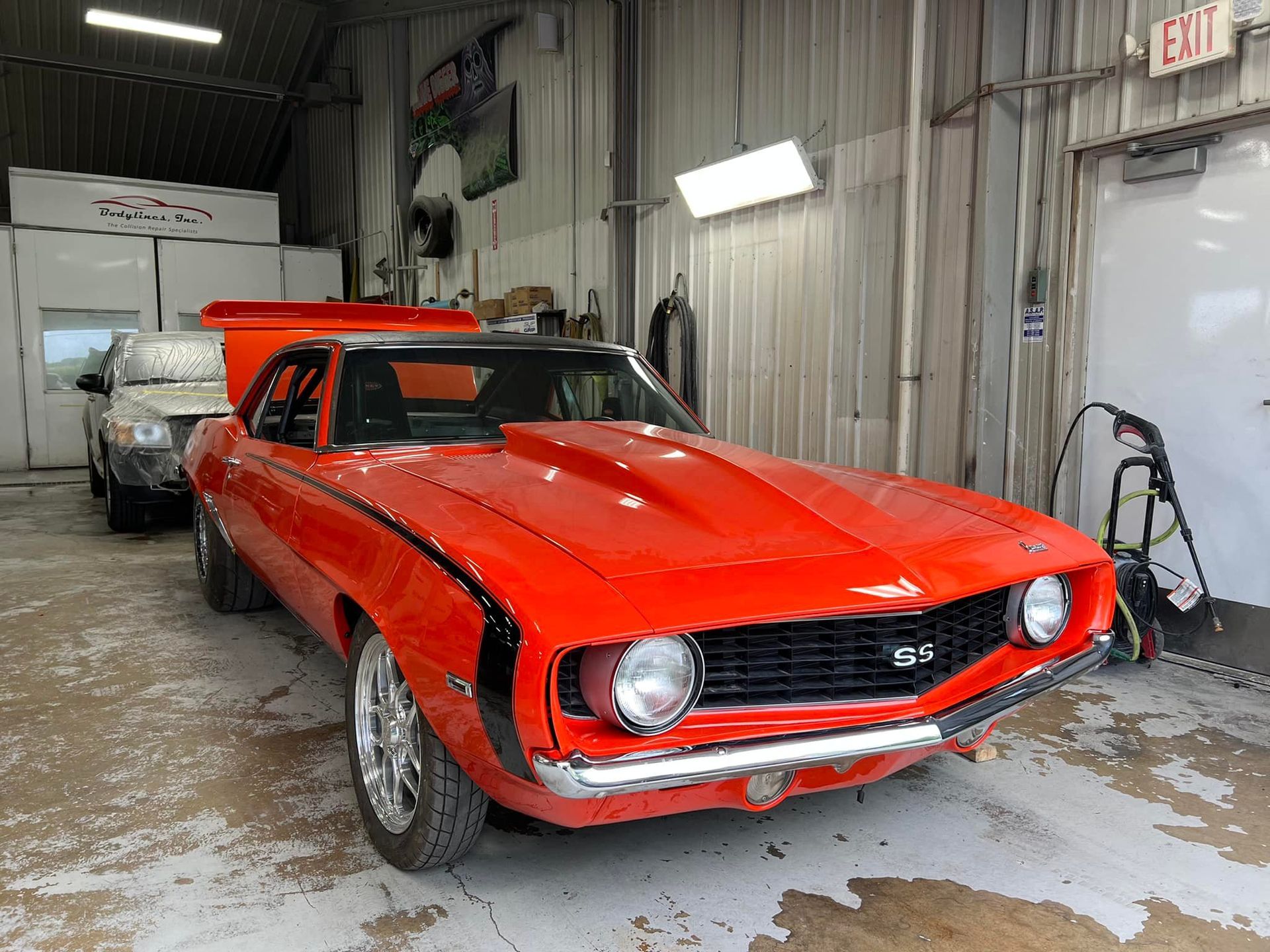 Bright orange classic car in a garage with silver wheels.