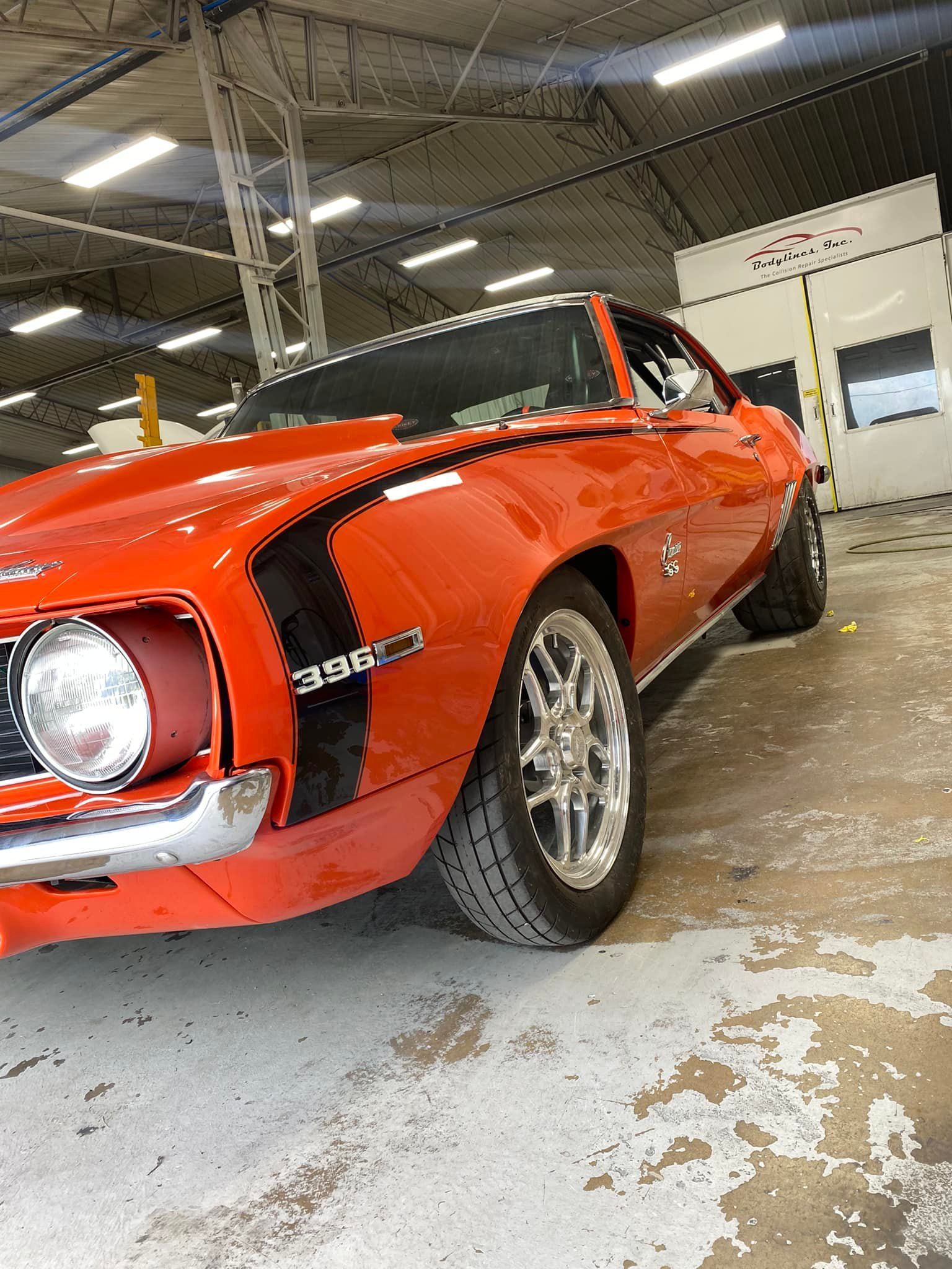 Orange classic Chevrolet Camaro in a garage.