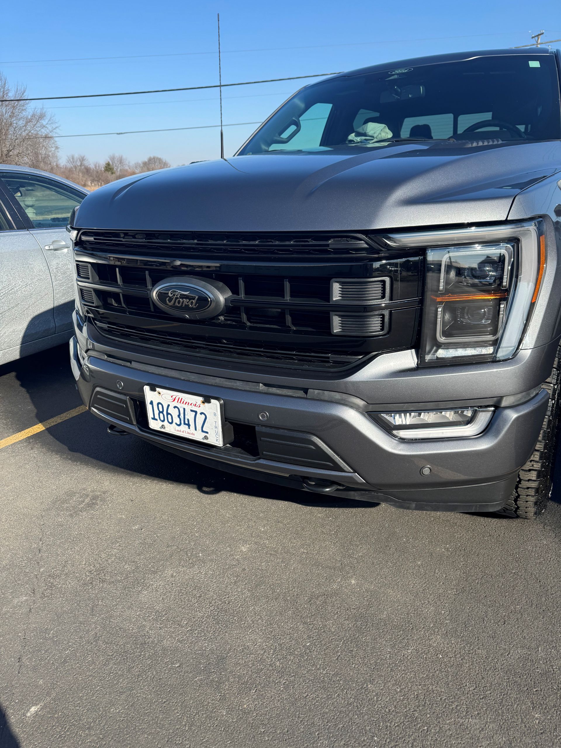 White pickup truck, rear view, in a shop, black tire, silver wheel, black bed cover, and red tail light - After
