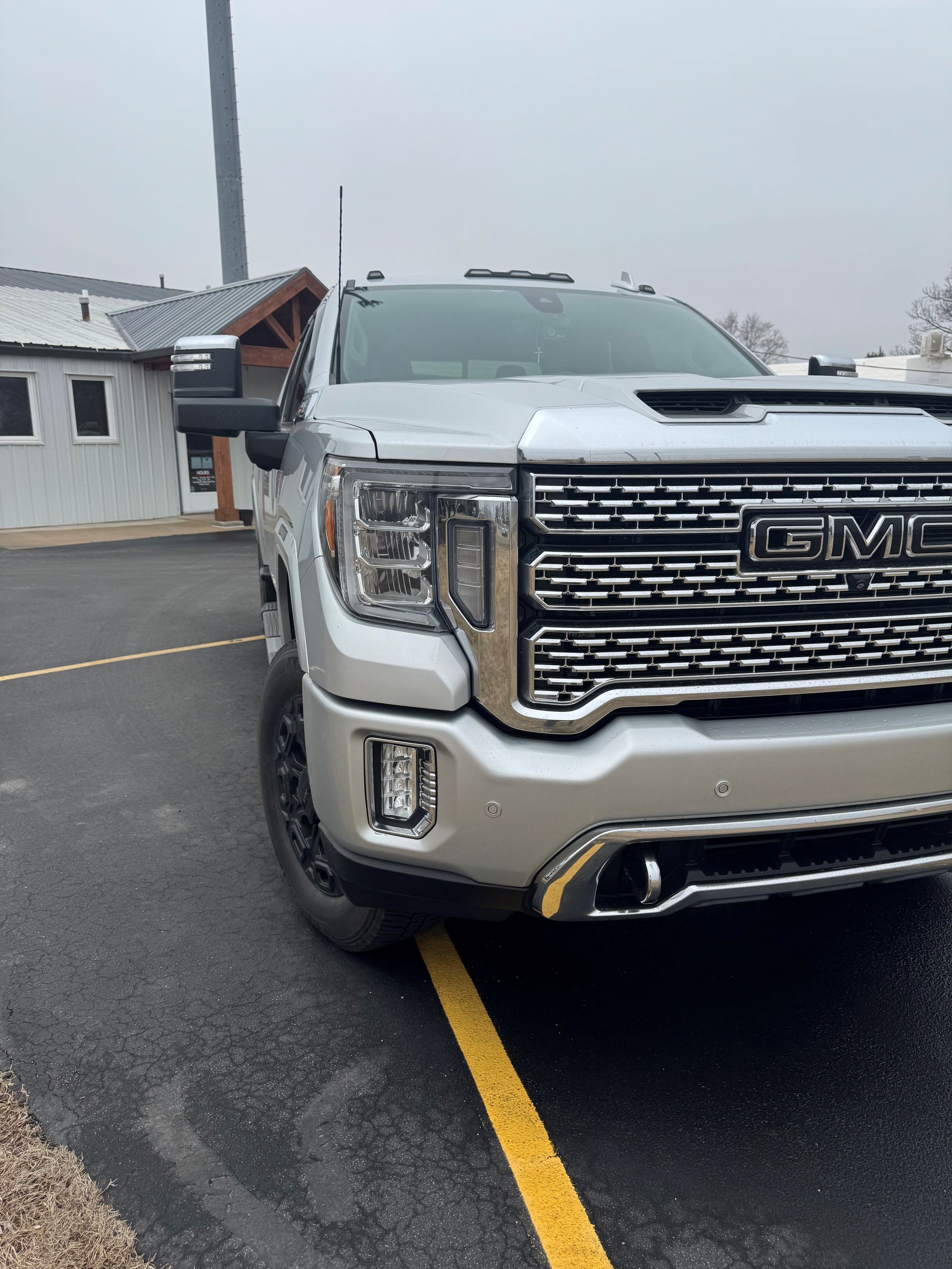 White pickup truck, rear view, in a shop, black tire, silver wheel, black bed cover, and red tail light - After