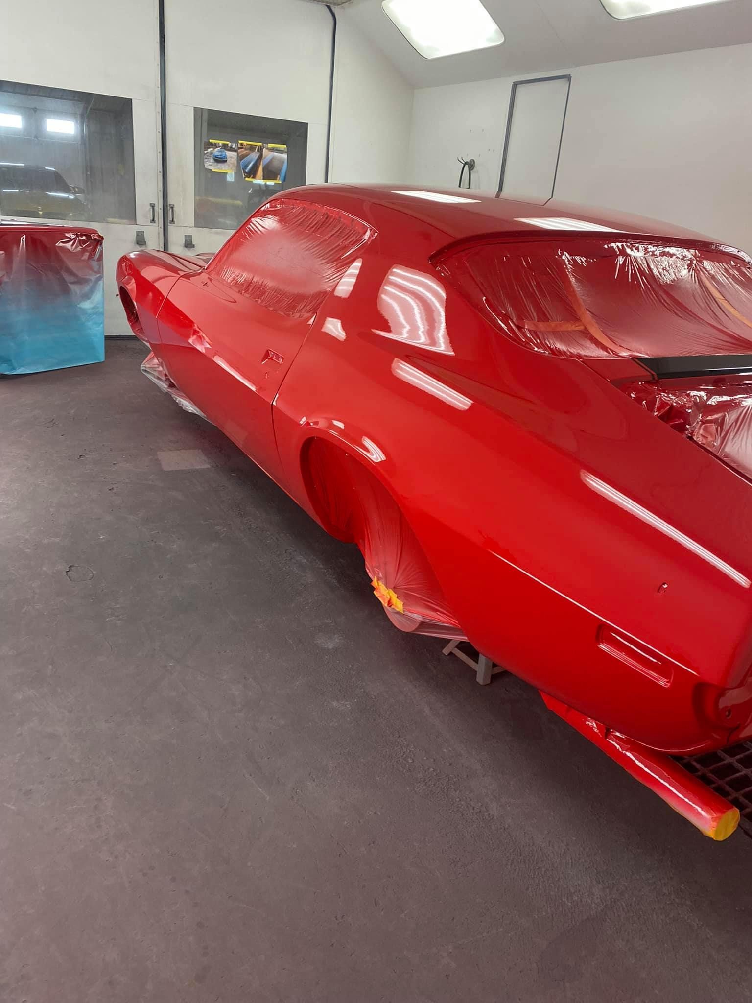 Red classic car in a paint booth.