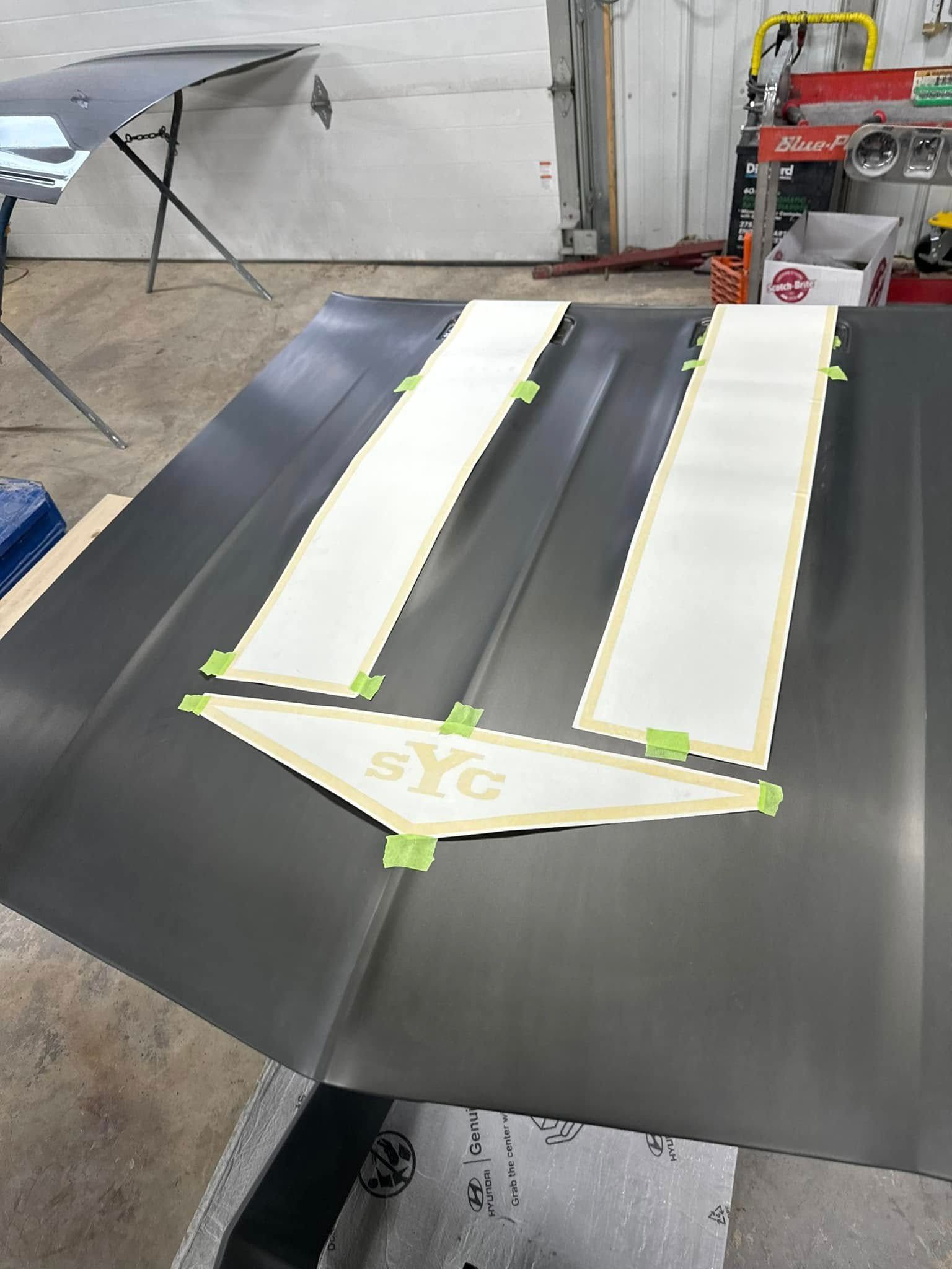 Dark car hood with masking for a white stripe design and 