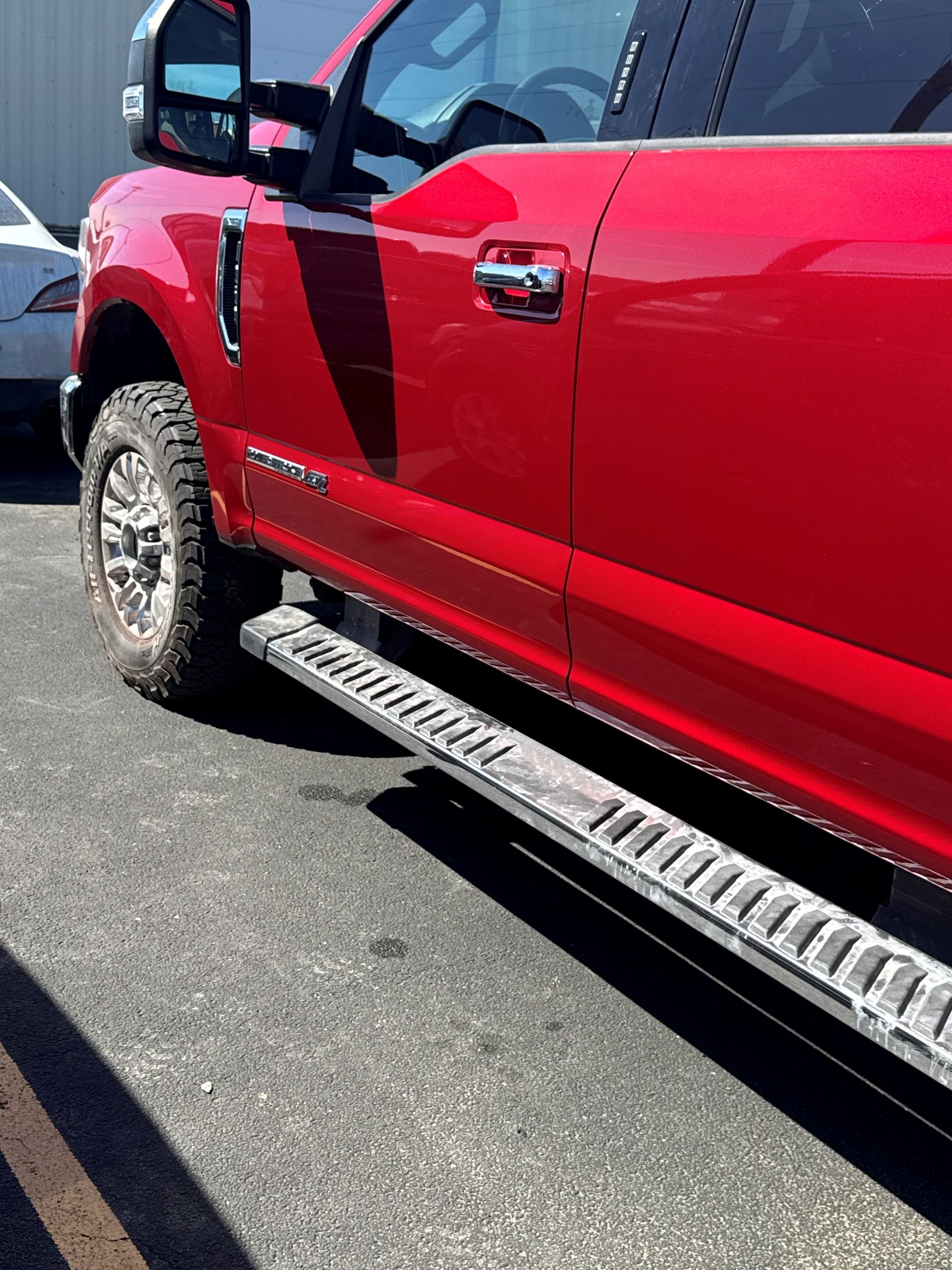Red pickup truck with chrome running board parked on asphalt.