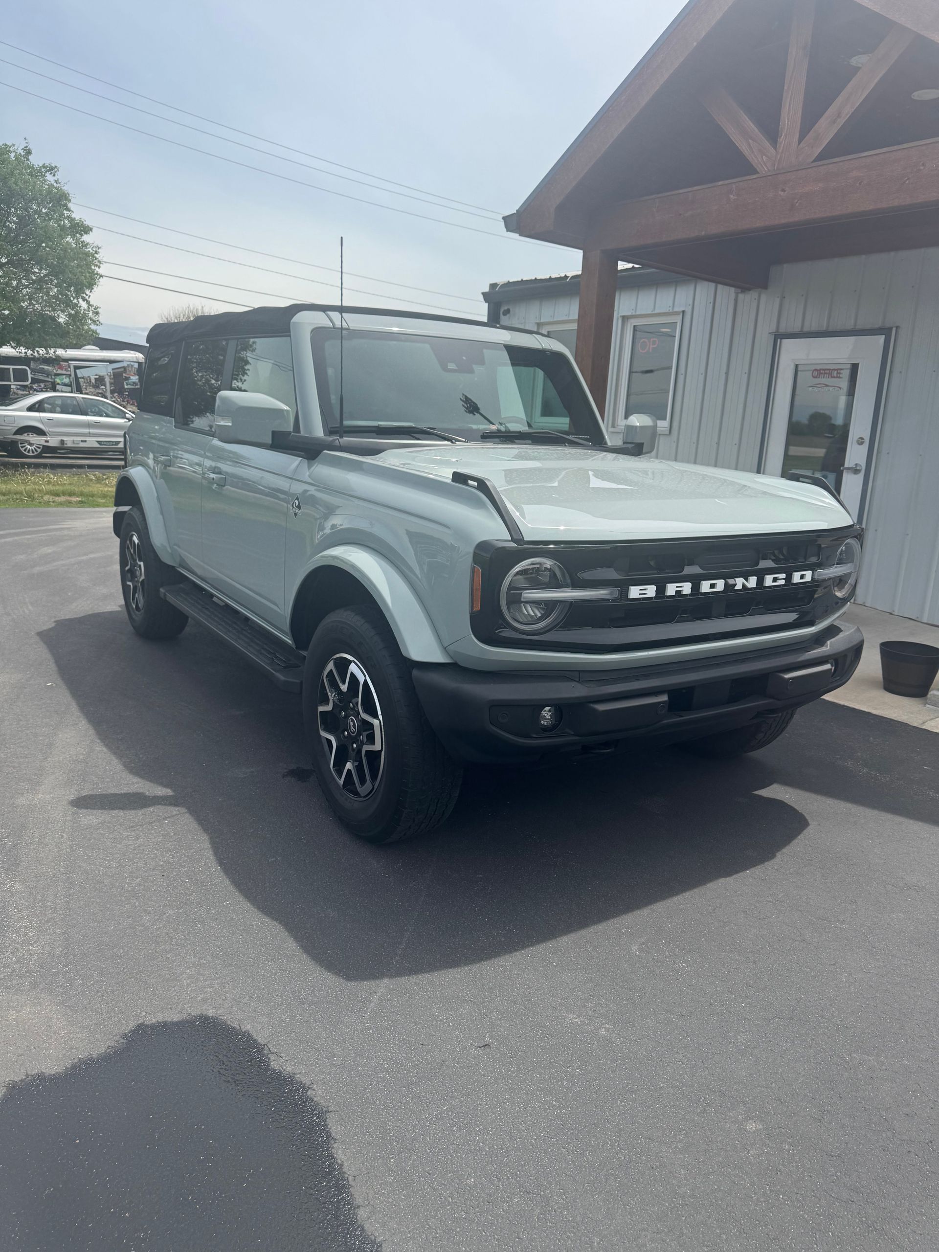 Green Ford Bronco parked beside a building in a lot, front three-quarter view.