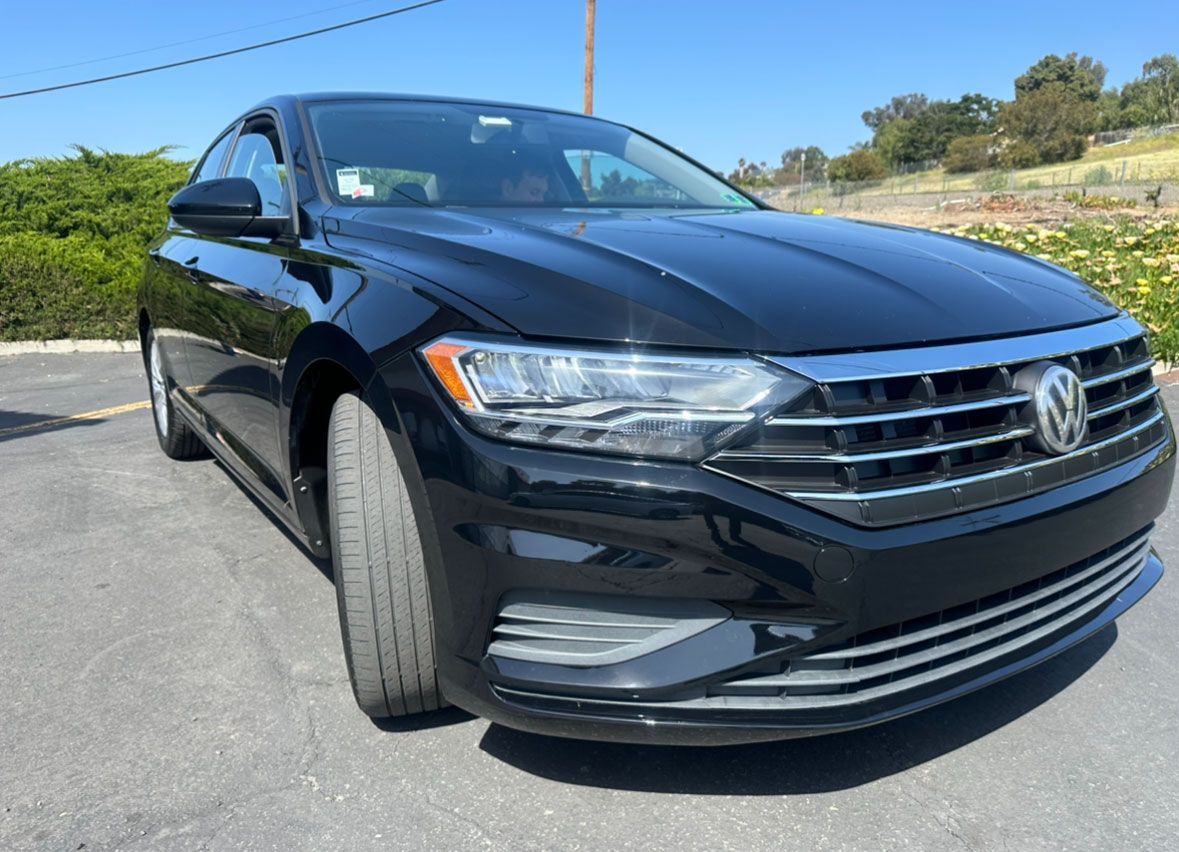 A black volkswagen jetta is parked in a parking lot.
