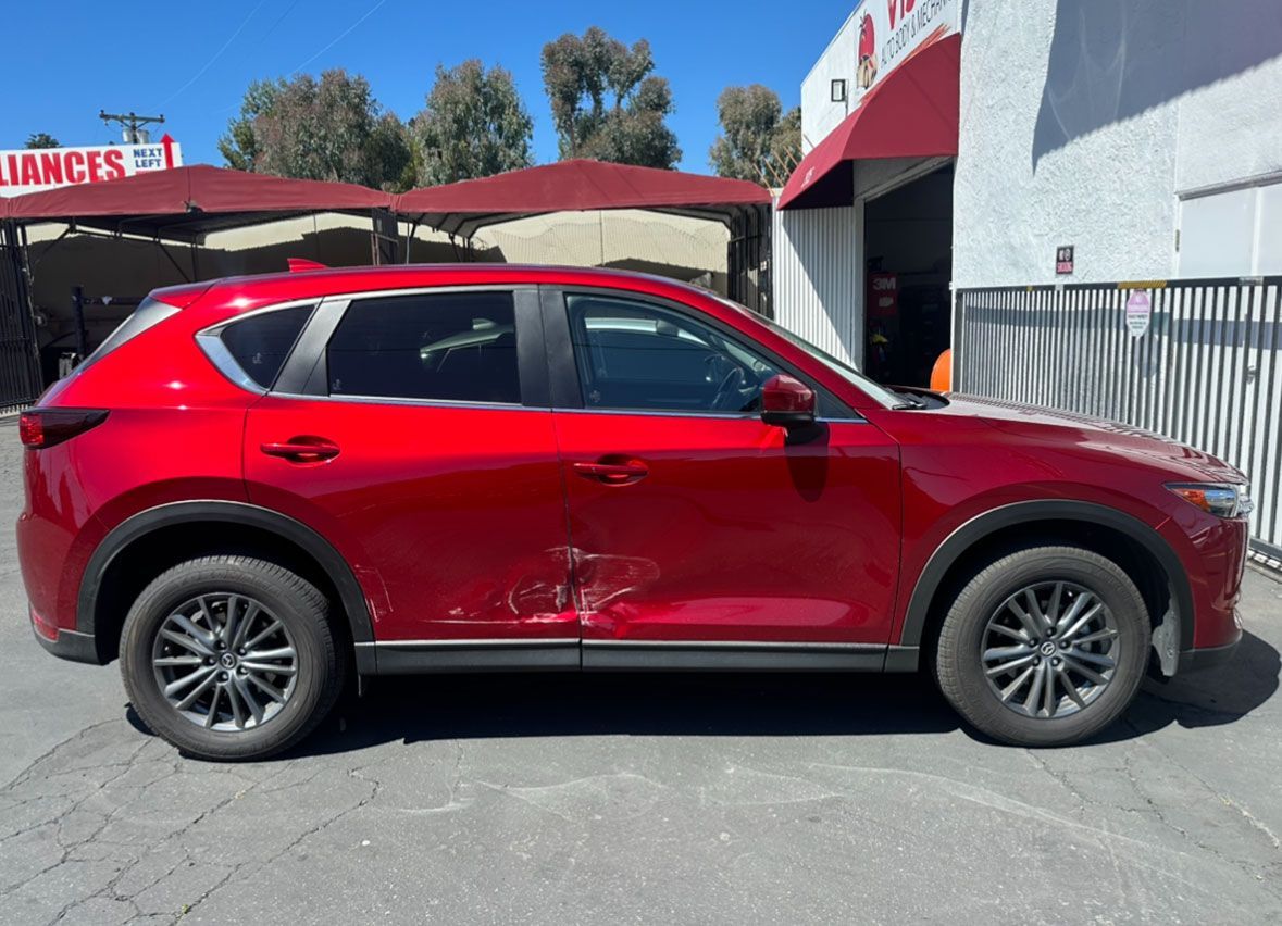 A red car is parked in front of a building.