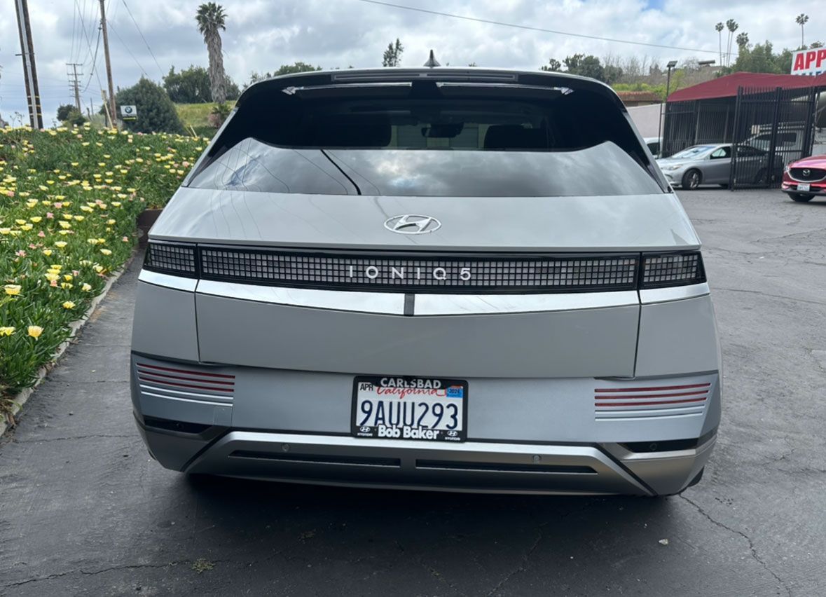 A hyundai ioniq 5 is parked in a parking lot next to a field of flowers.