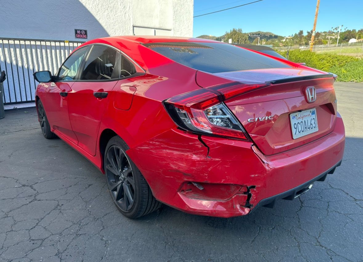 A red honda civic is parked in front of a building.