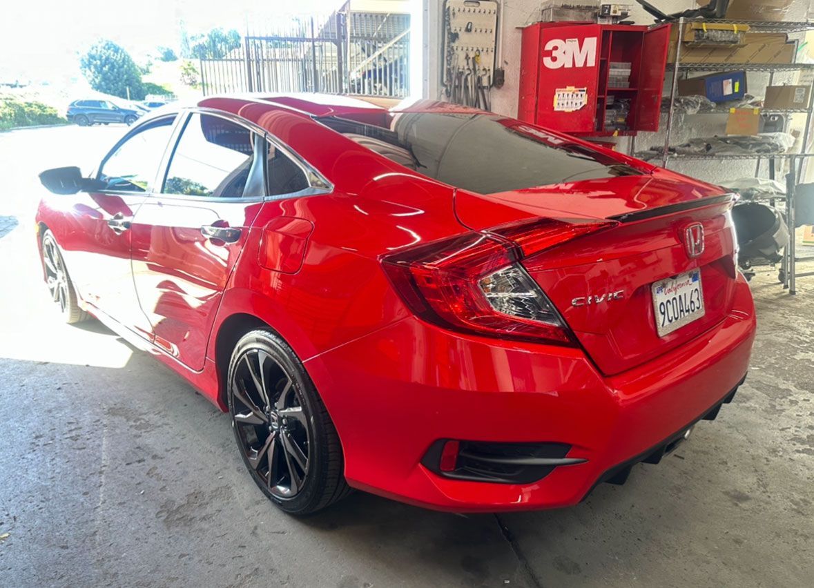A red honda civic is parked in a garage.