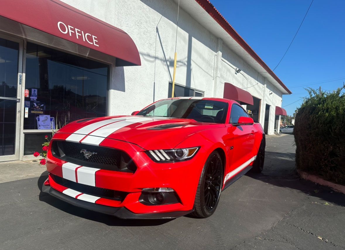 A red mustang is parked in front of an office building