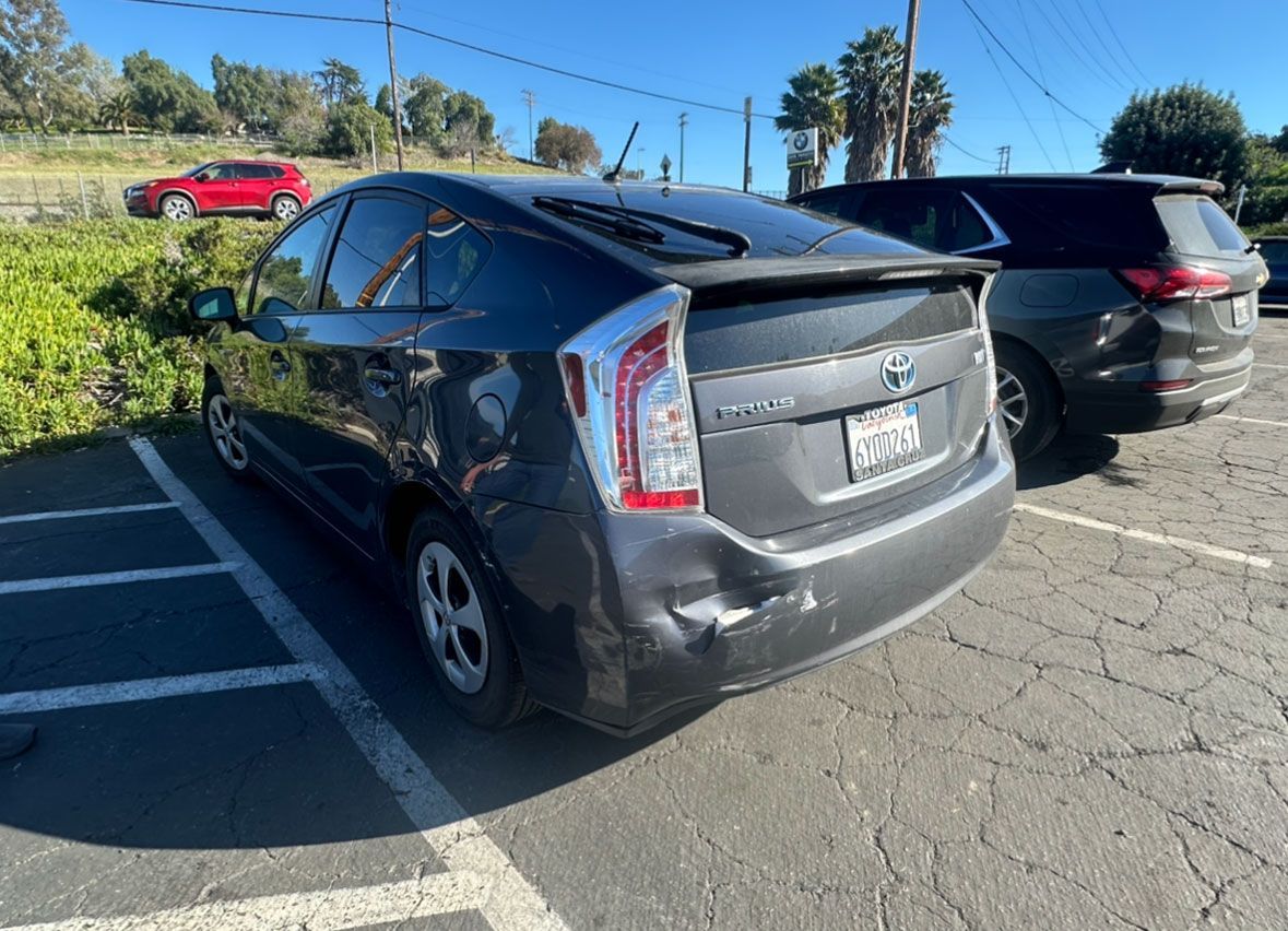 A toyota prius is parked in a parking lot next to another car.