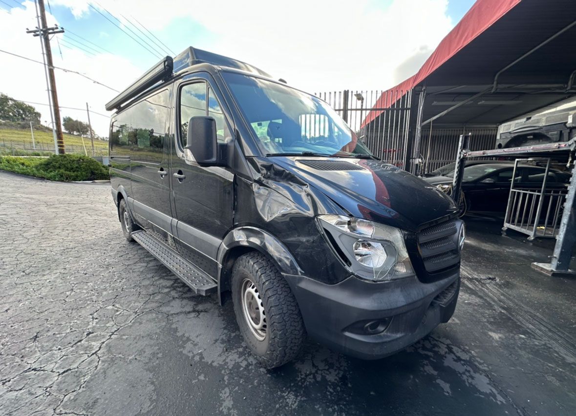 A black van is parked in a parking lot in front of a building.