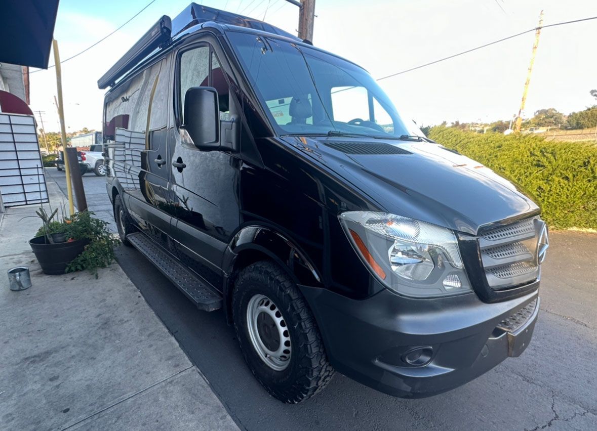 A black van is parked on the side of the road.