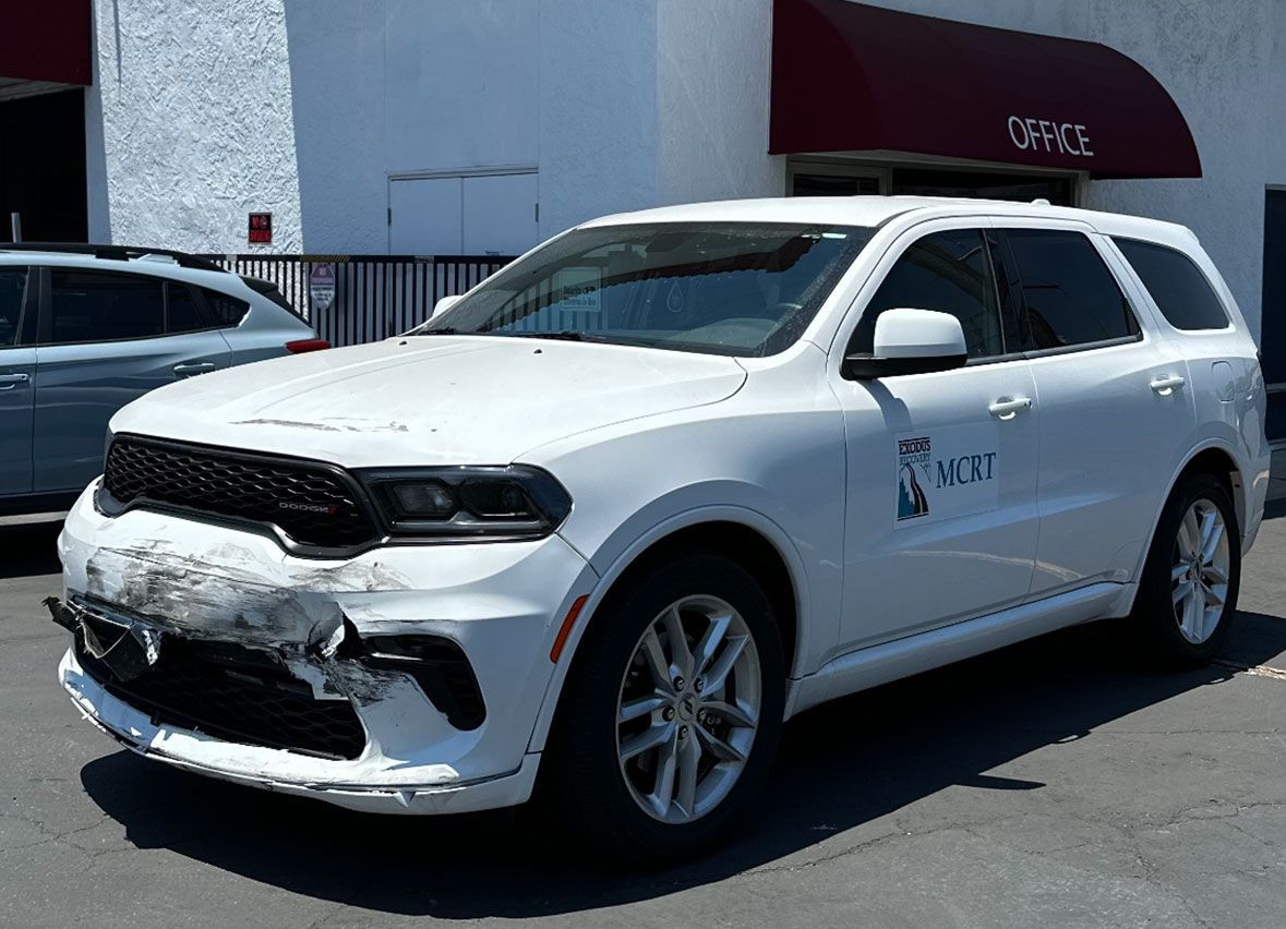 A white dodge durango is parked in front of a building.