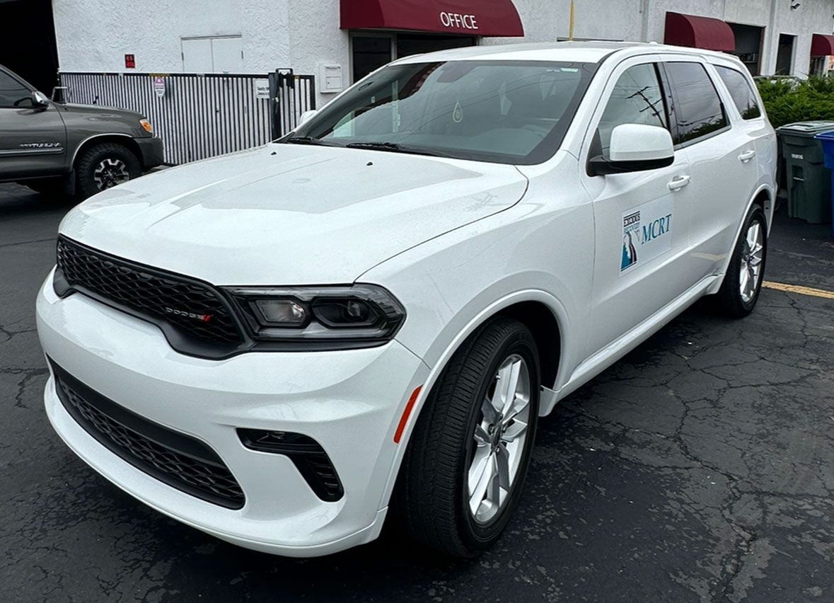 A white dodge durango is parked in a parking lot in front of a building.