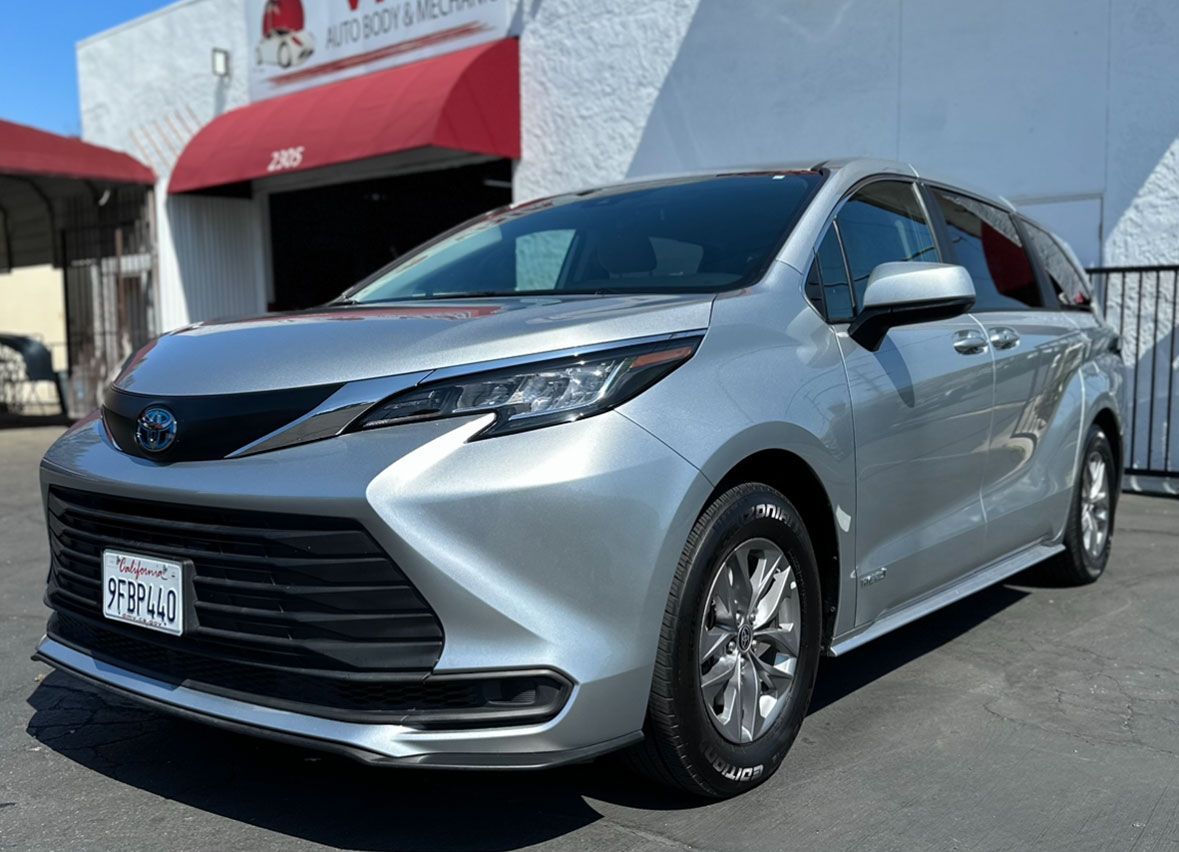 A silver toyota sienna minivan is parked in front of a building.