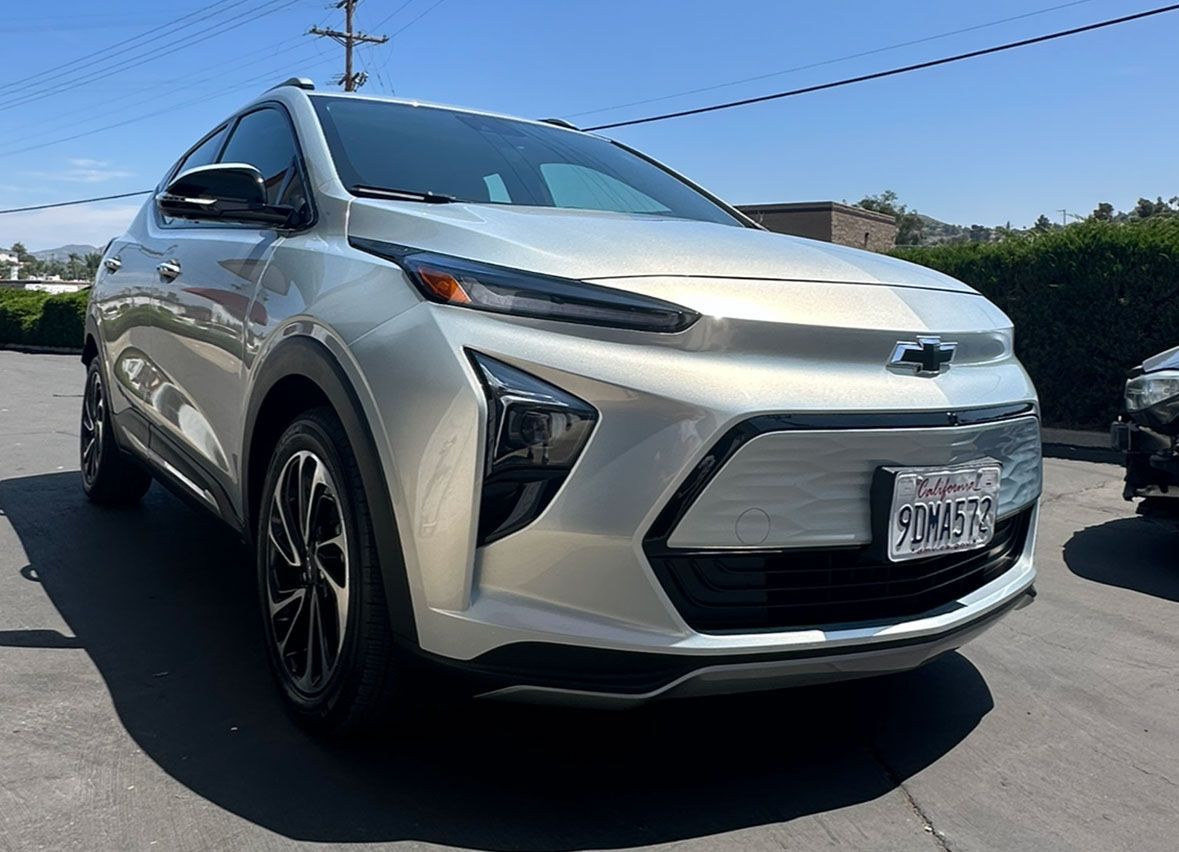 A silver chevy bolt electric car is parked in a parking lot.