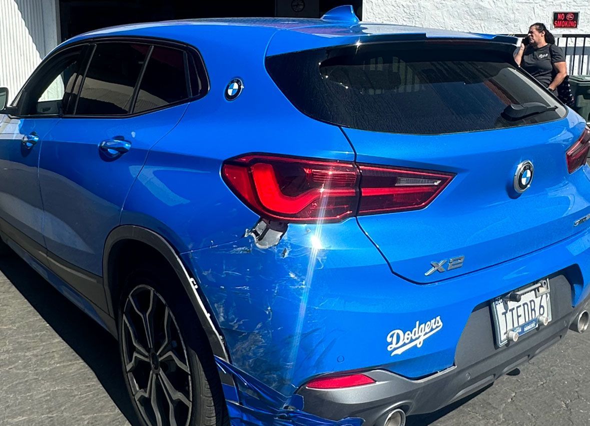 A blue car with a dodgers sticker on the back