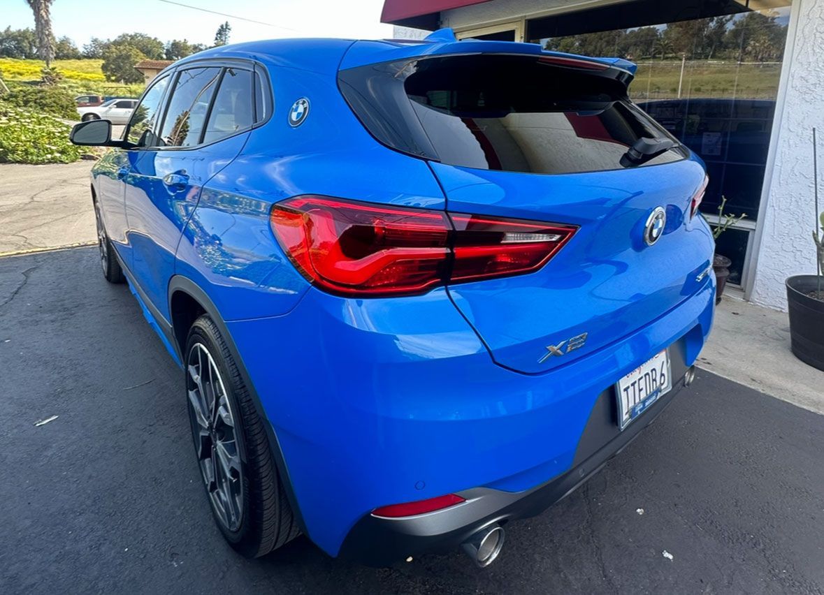A blue bmw x2 is parked in front of a building.
