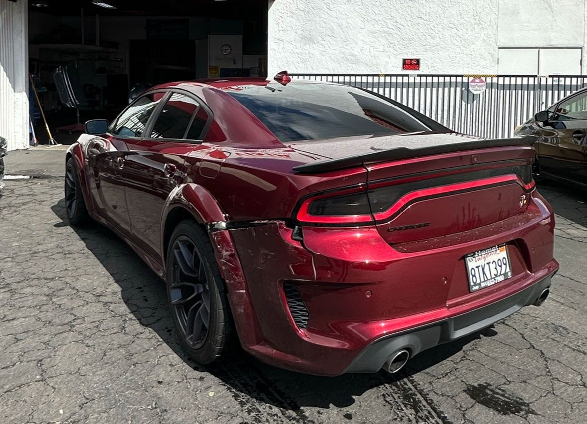A red dodge charger is parked in front of a garage.