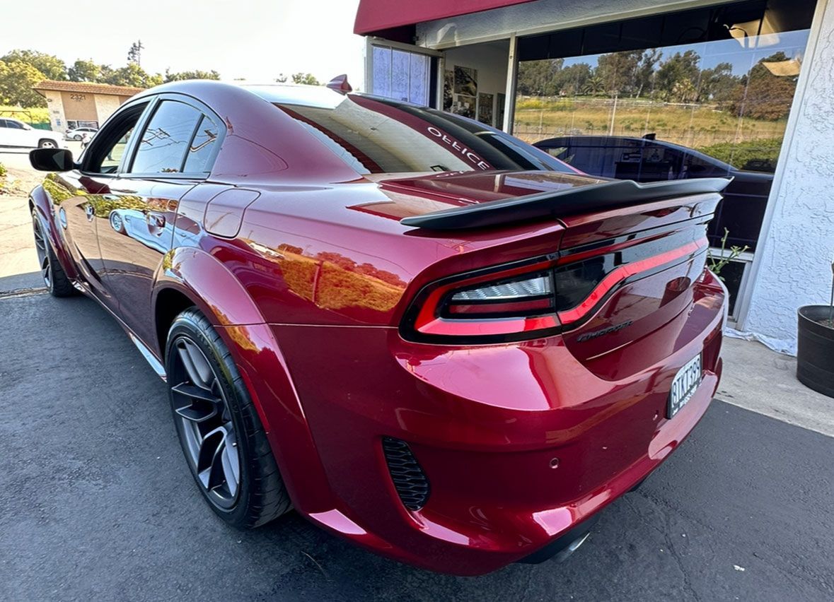 A red dodge charger is parked in front of a building.