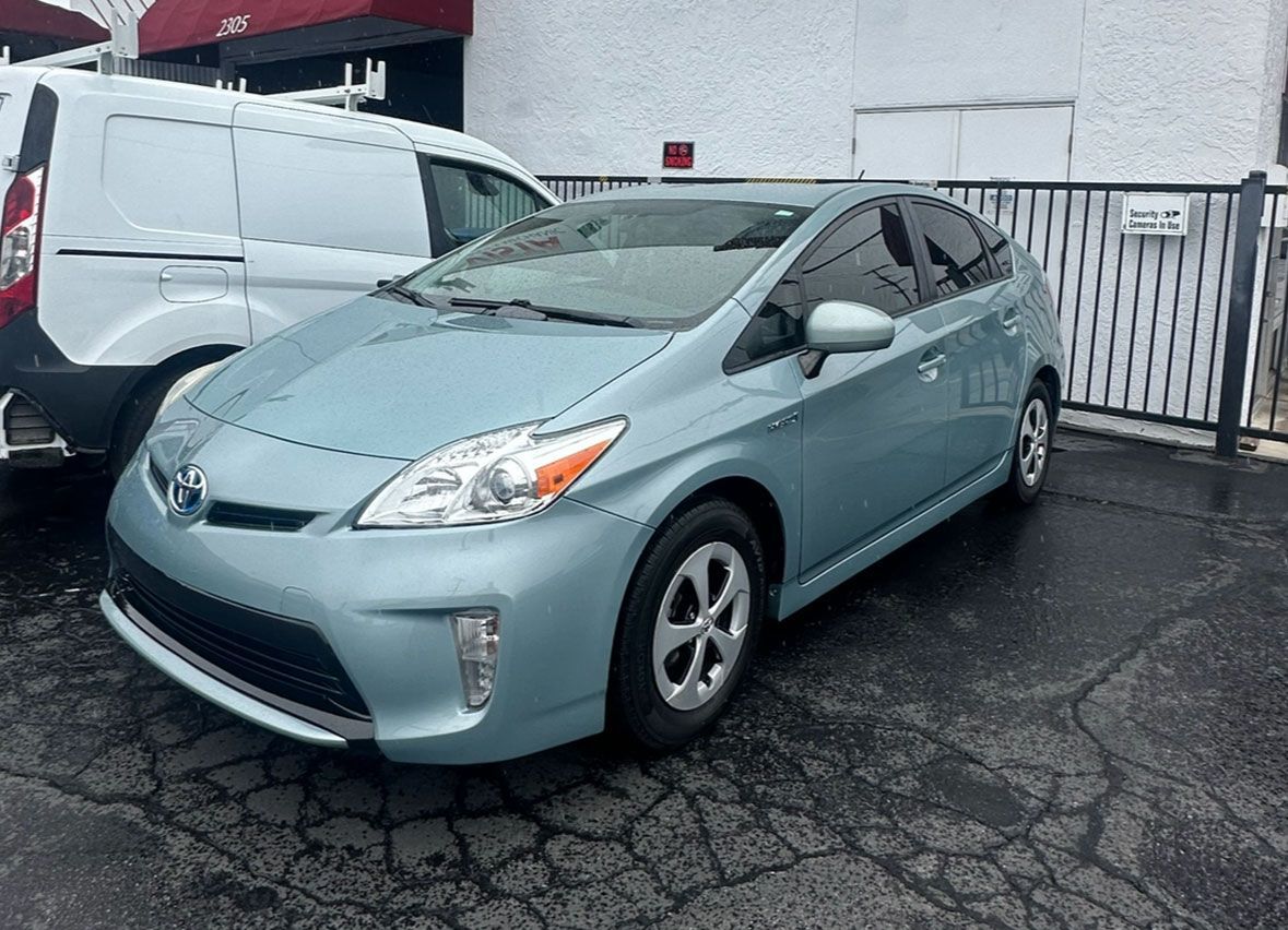A blue toyota prius is parked in front of a building.