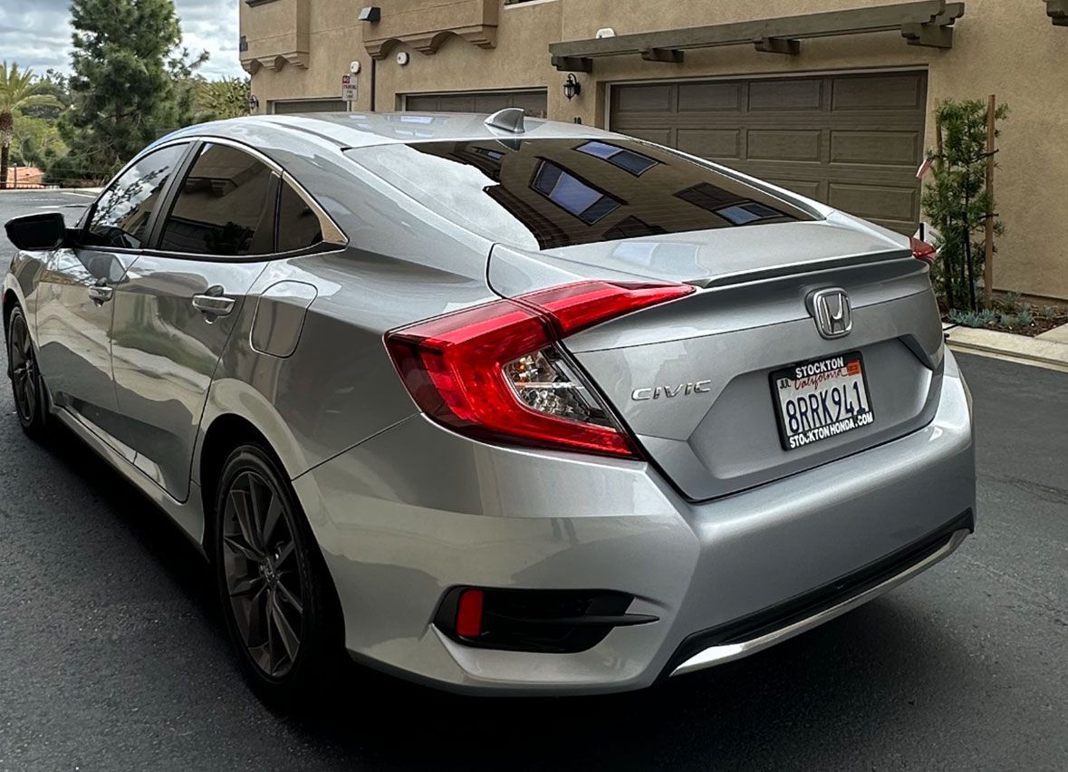 A silver honda civic is parked in front of a garage.