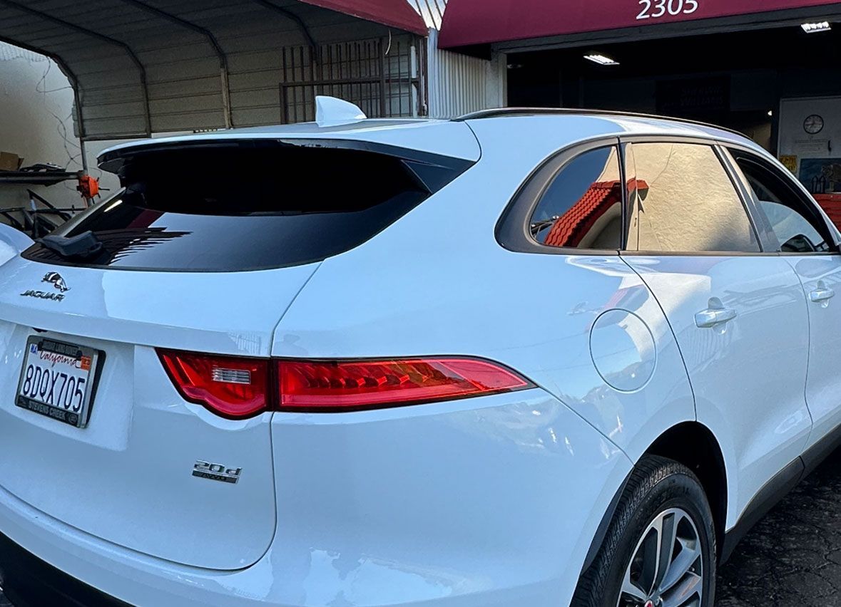 A white jaguar f pace is parked in front of a garage.