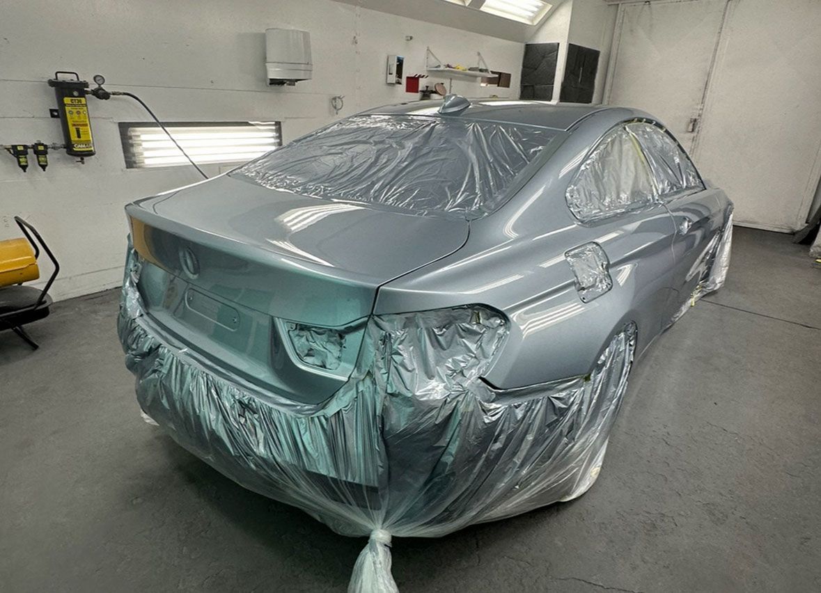 A car is covered in plastic wrap in a garage.