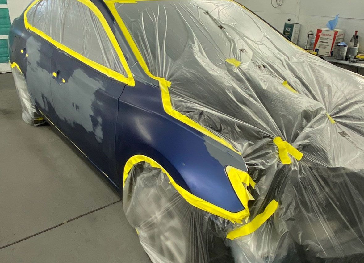 A blue car is covered in plastic and yellow tape