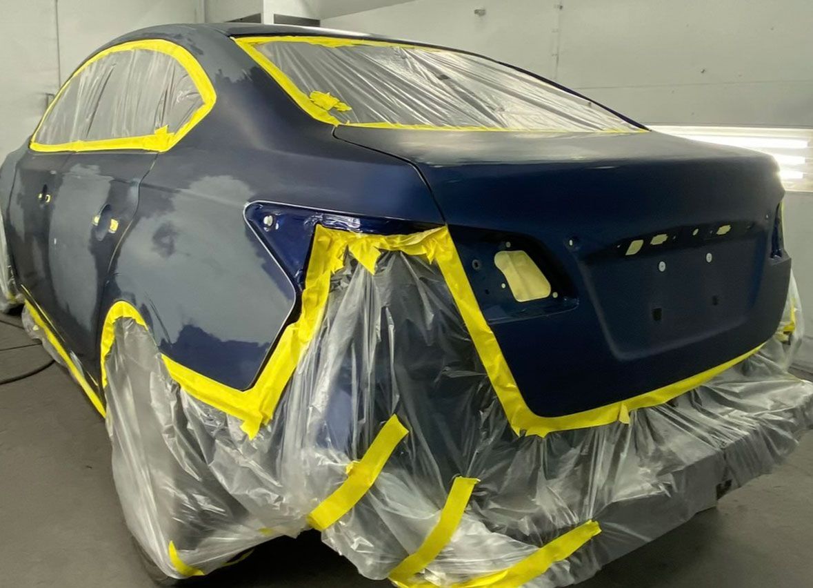 A blue car is covered in plastic and yellow tape.