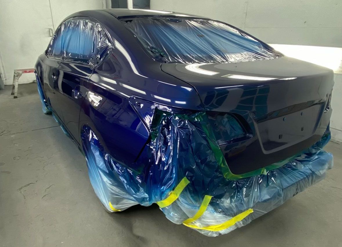 A blue car is wrapped in plastic and tape