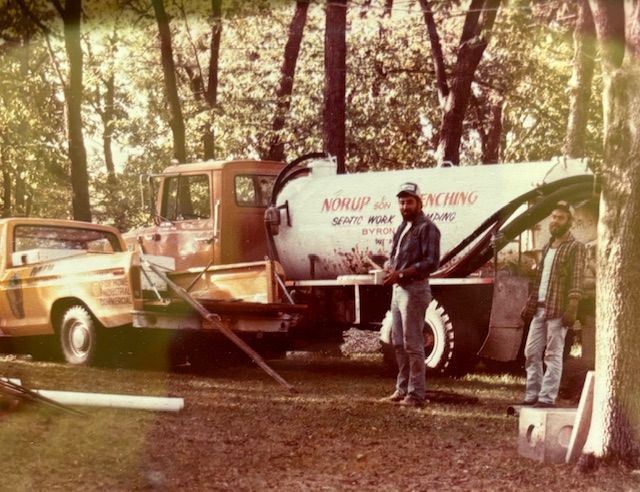 A man is standing in front of a truck that says air pump