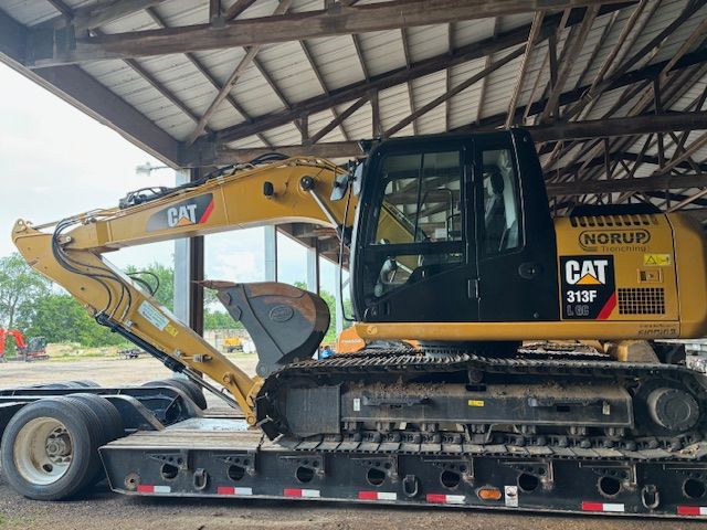 A cat excavator is on a trailer under a roof